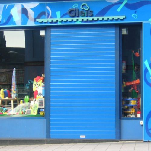 Puerta metálica azul para comercio con fachada en misma tonalidad